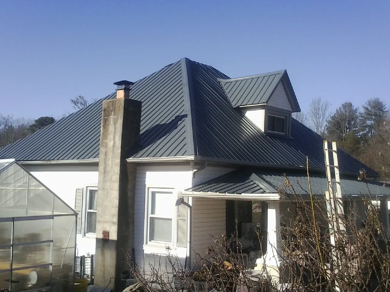 Dark blue standing seam metal roof on a white farmhouse with dormer — Slate & Tile Roof Repair by Roofing Brothers in Island Heights