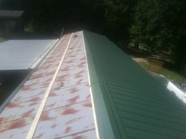 Old rusted panels beside newly installed green metal roofing — Wind Damage Roof Repair by Roofing Brothers in Island Heights