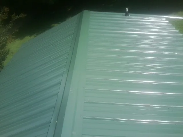 New green metal panels meeting at the ridge of a roof — Flat Roof Repair work by our crew in Island Heights