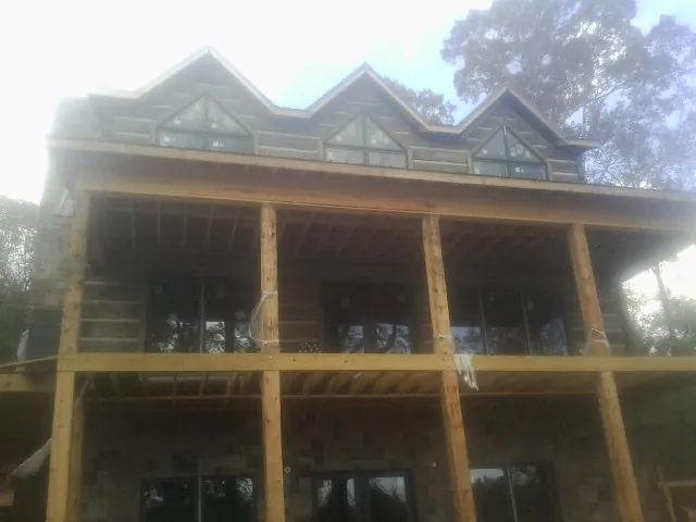 Dormers and porch framing on a large log home under construction — Roof Coating work by our crew in Island Heights