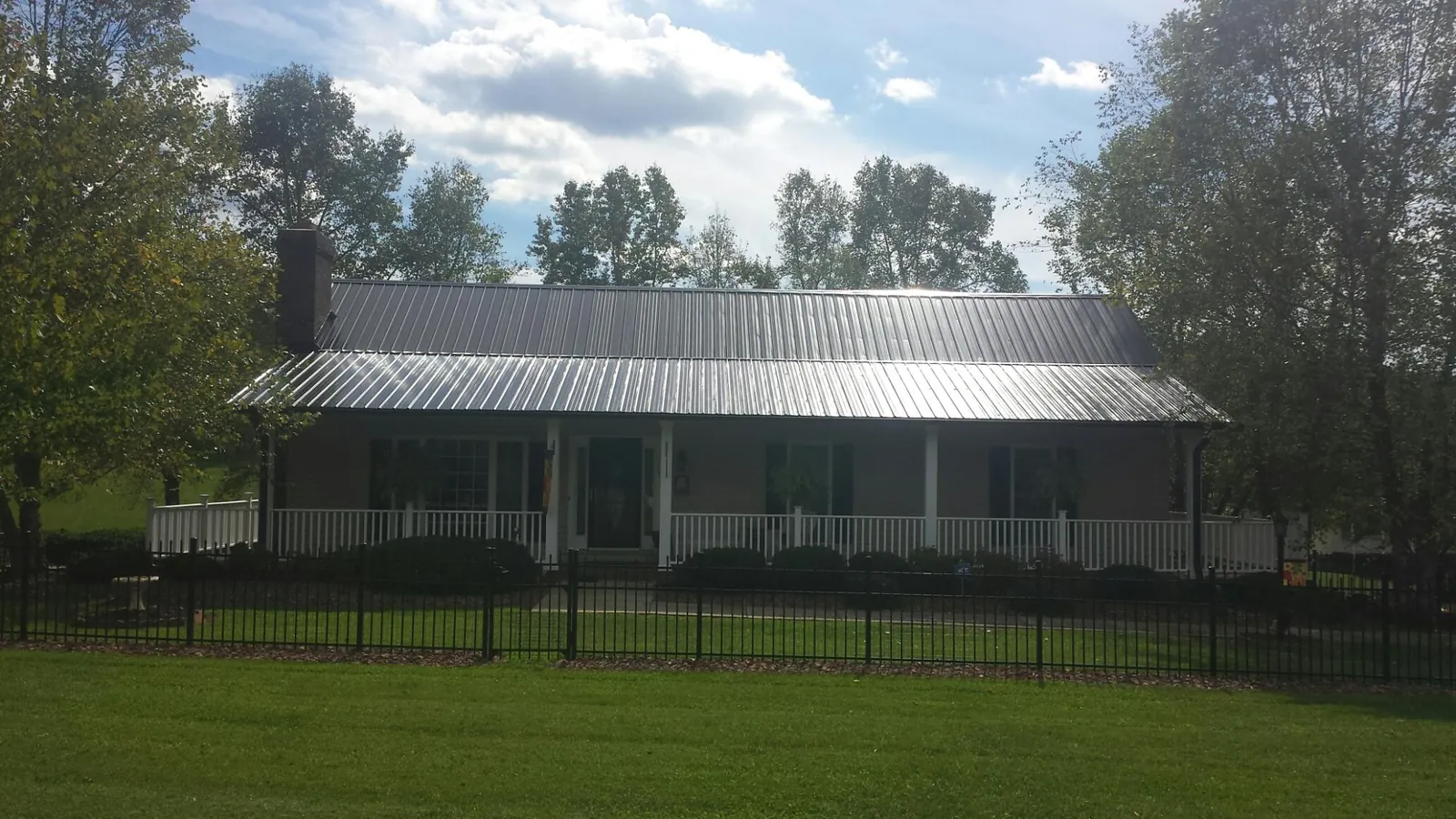 Gray metal roof on a brick ranch with a full width front porch — Gutter Guard Installation work by our crew in Island Heights