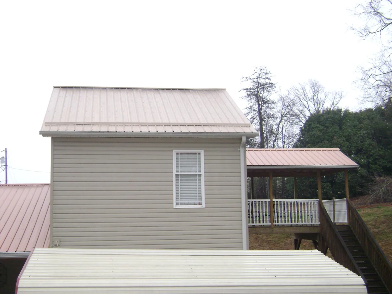 Tan metal roofs on a two story addition and attached porch, from a Roof Replacement job in Island Heights