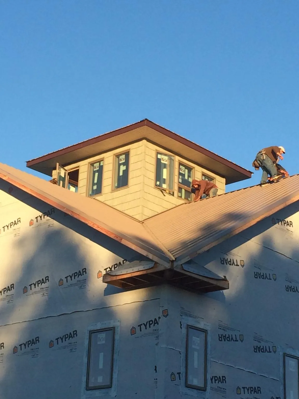 Roofers working around a rooftop cupola on a new metal roof at sunset — Roof Waterproofing in Island Heights by Roofing Brothers